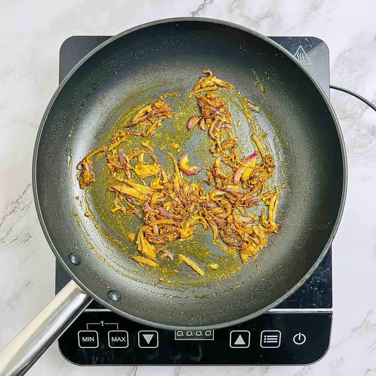 Sauted onion and spices in a frying pan.