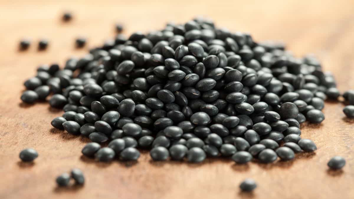 Black lentils on a wooden board.