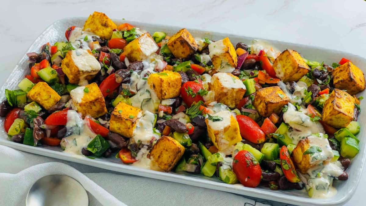 Paneer tikka and rajma salad on a rectanular serving plate.