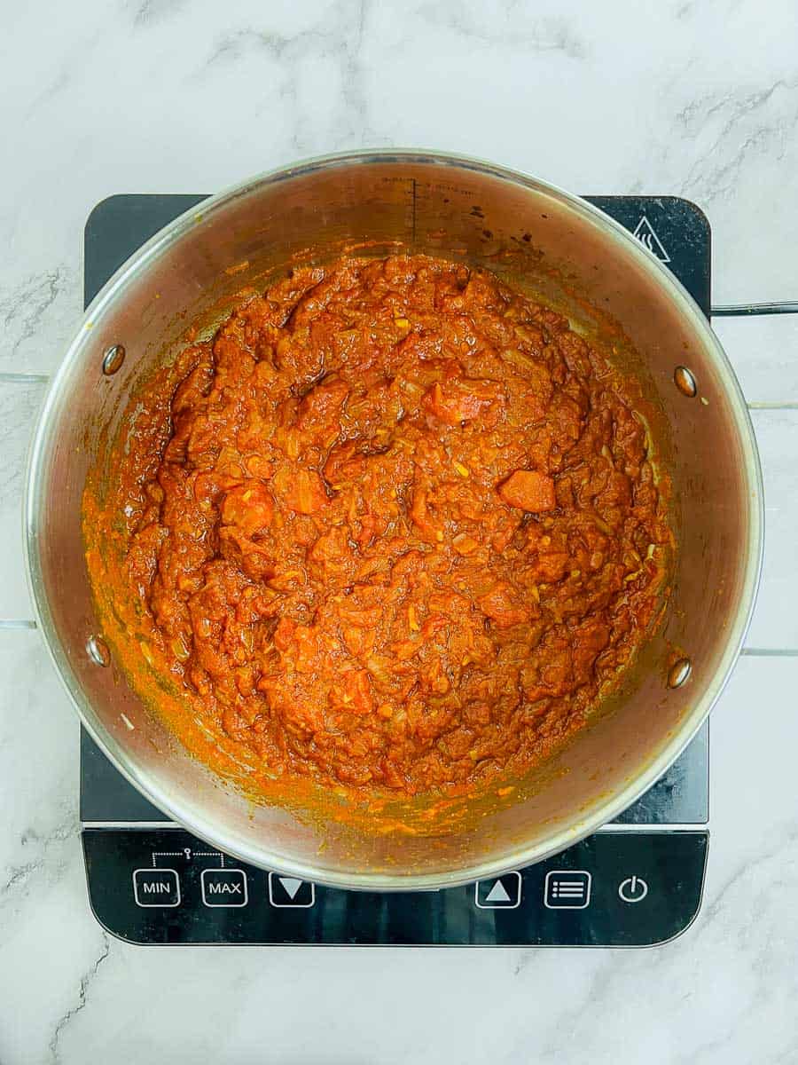 Tomato and spices cooked with onions in the pot.