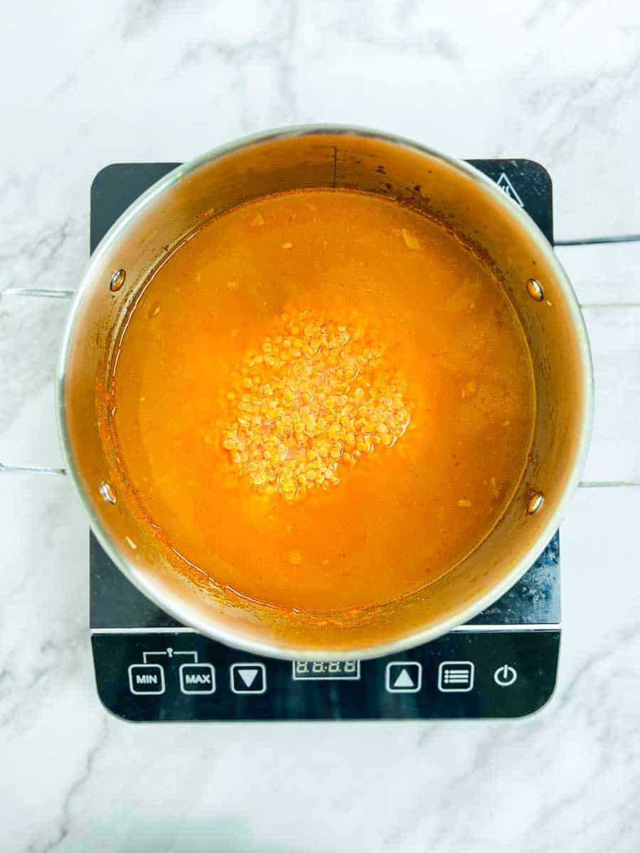 Red lentils and water added to the onion-tomato masala in the pot.