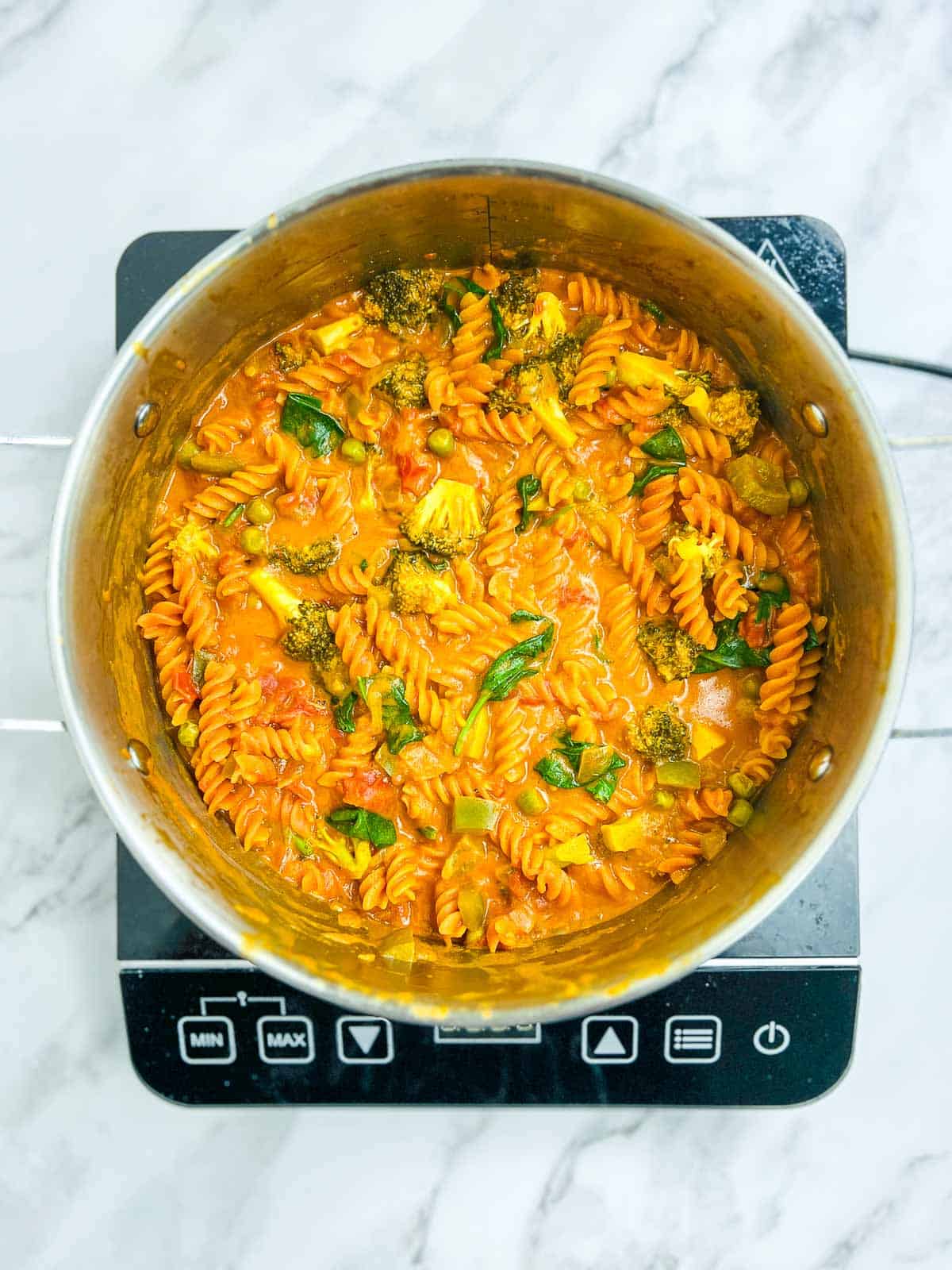 Coconut milk and spinach mixed into the cooked pasta in the pot.