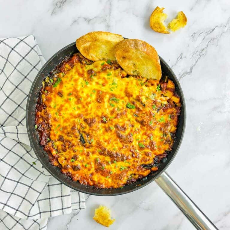 White bean and tomato bake in a skillet with crusty bread.