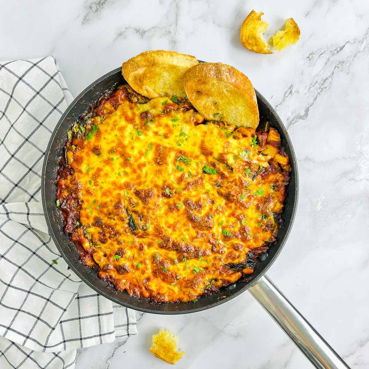White bean and tomato bake in a skillet with crusty bread.