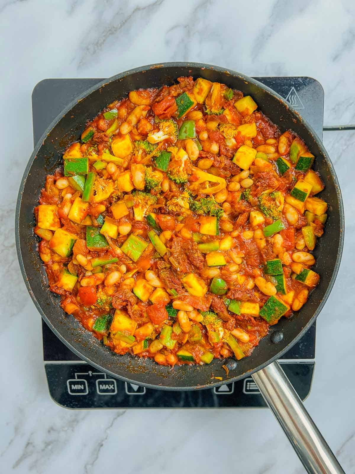 Cooked tomatoes, beans, and veggies in the skillet.