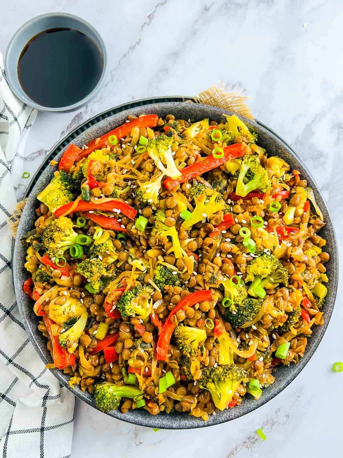 Broccoli lentil stir fry with soy sauce in the background.