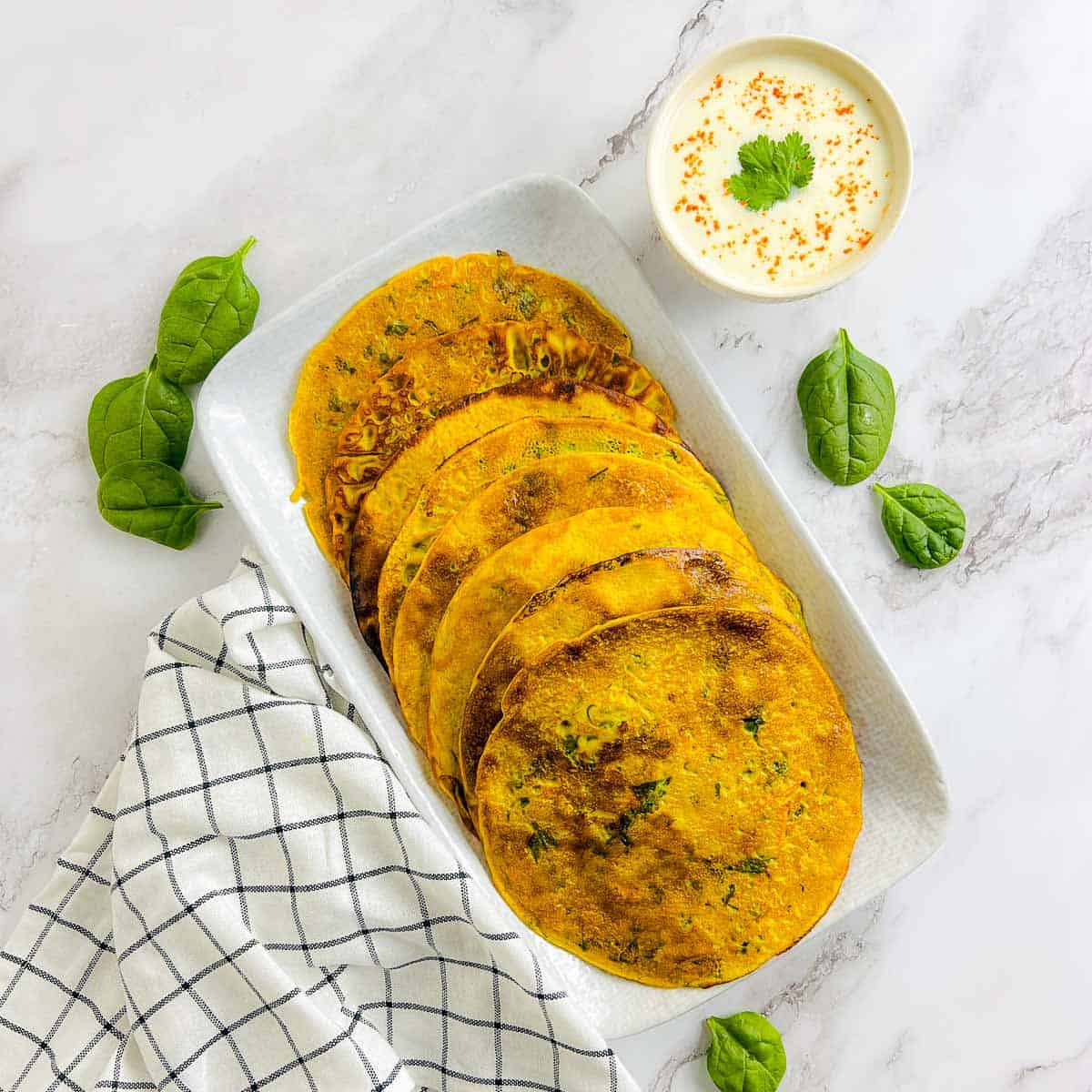 Stack of chickpea flour pancakes served with yogurt.