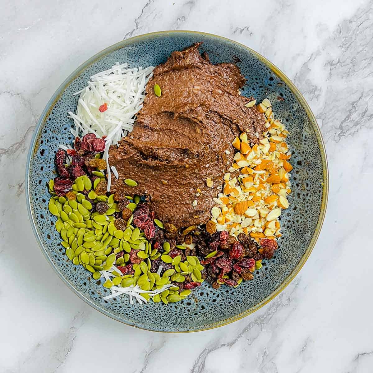 Lentil mixture combined with nuts, dried fruits, and shredded coconut in a mixing bowl.