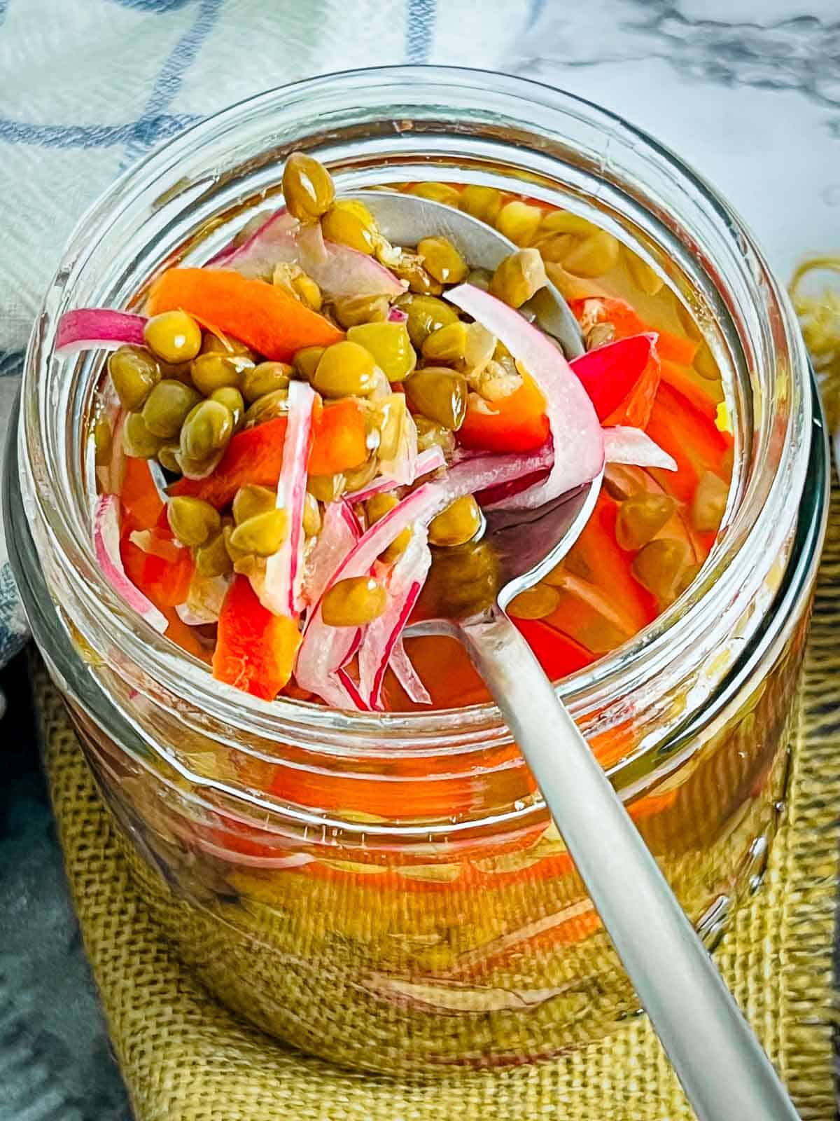 Pickled lentils taken on a spoon from the jar.