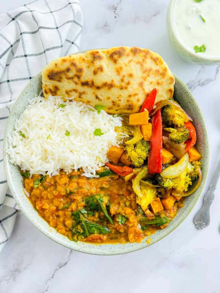 Red lentil dal Buddha bowl on a marble surface.