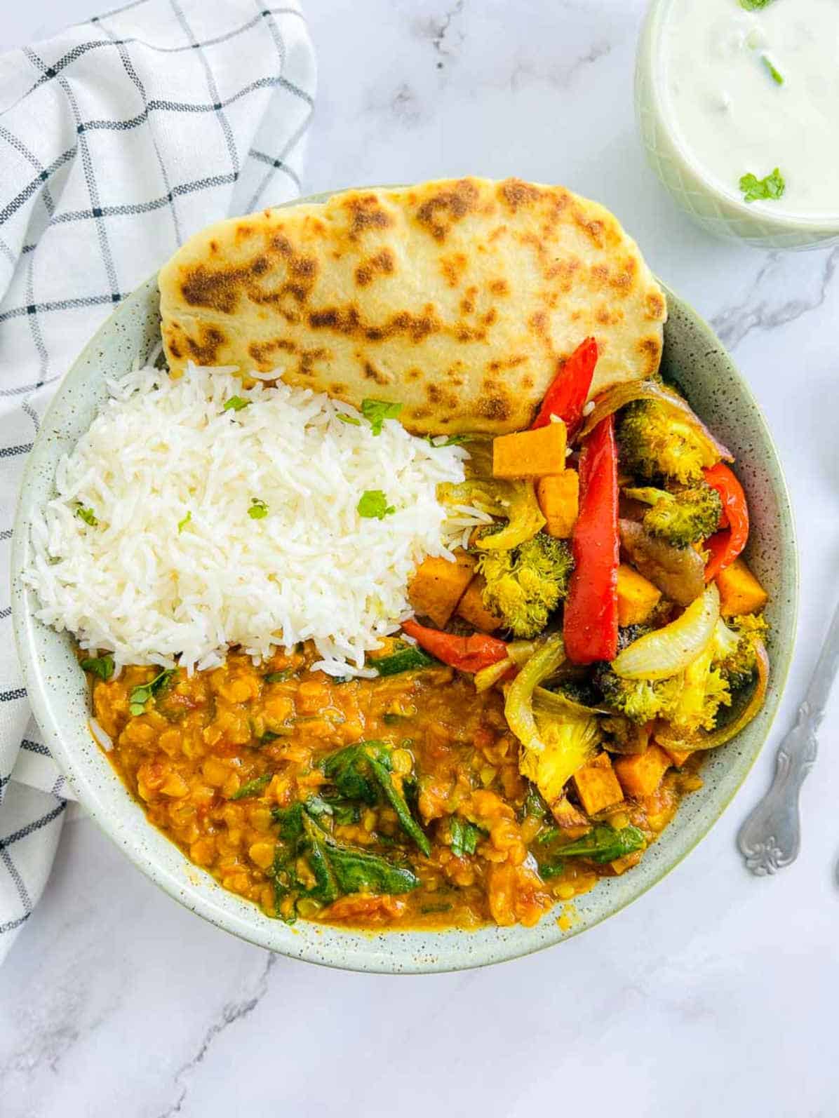 Red lentil dal Buddha bowl on a marble surface.