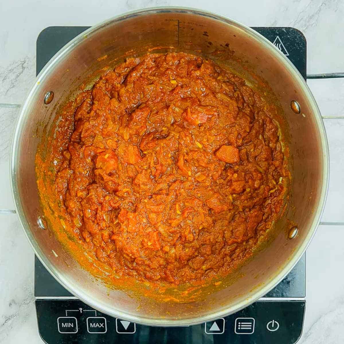 Onion, tomatoes, and spices cooked in a large pot.