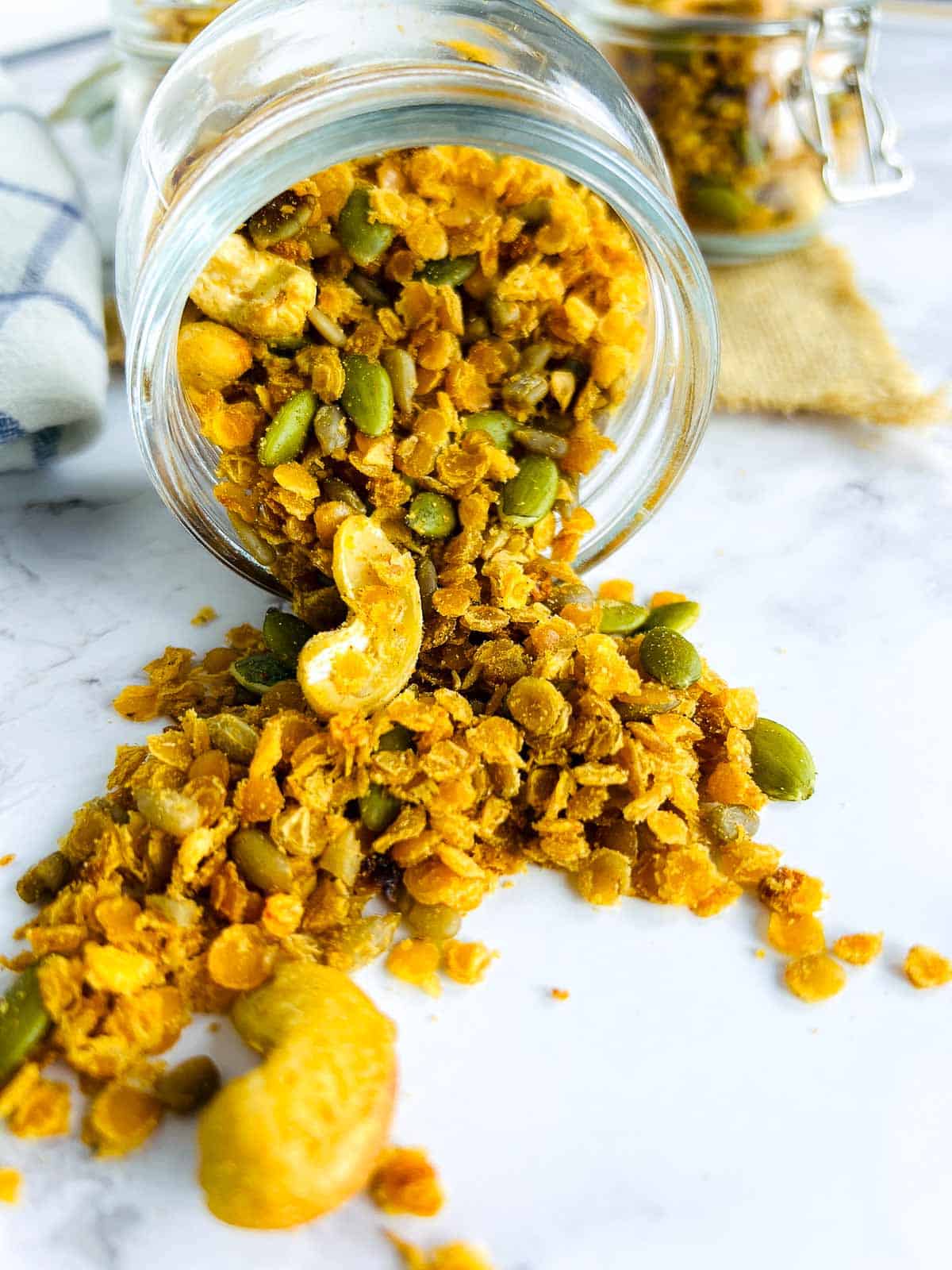 Red lentil granola falling from a glass jar.