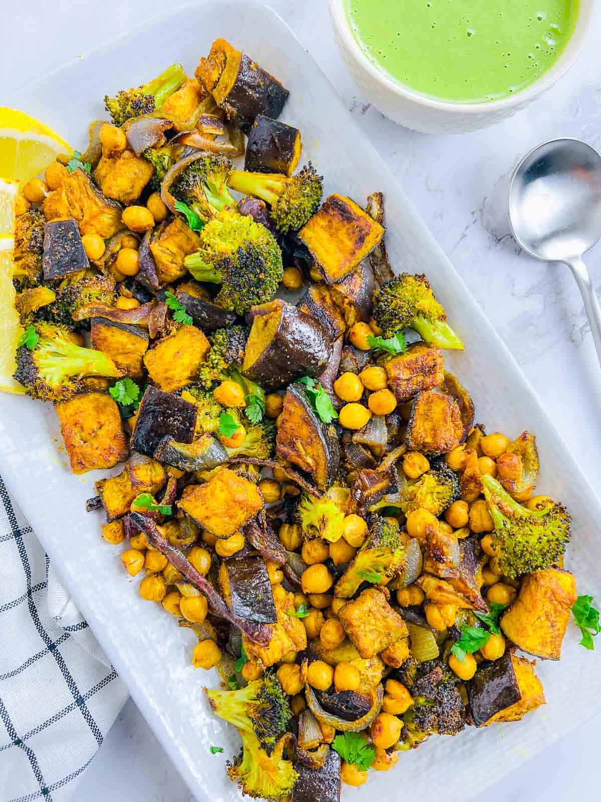 Roasted vegetables and chickpeas on a rectangular plate.