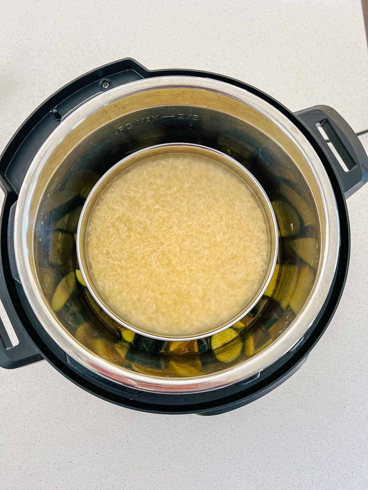 Rice-water bowl placed on a trivet over the dal and zucchini in the Instant Pot.