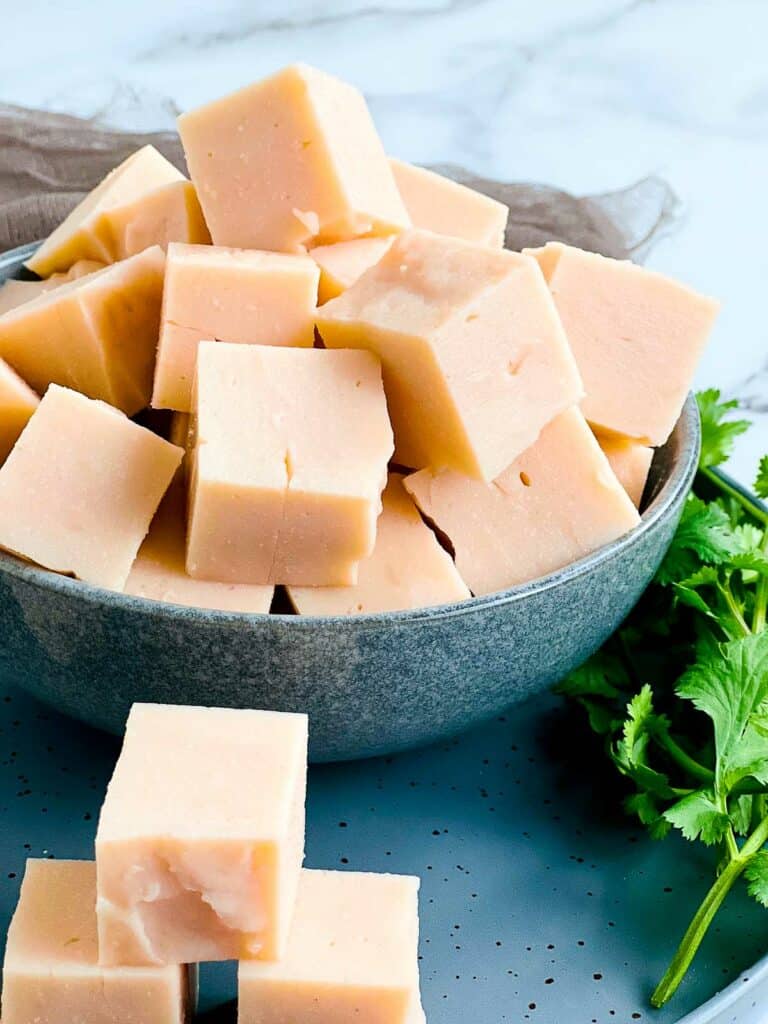 Cubes of red lentil tofu in a grey bowl.