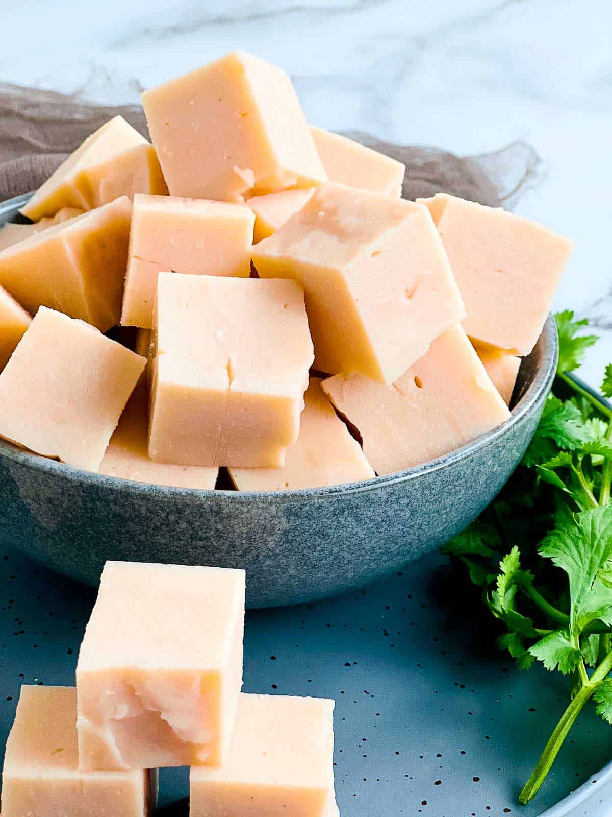 Cubes of red lentil tofu in a grey bowl.