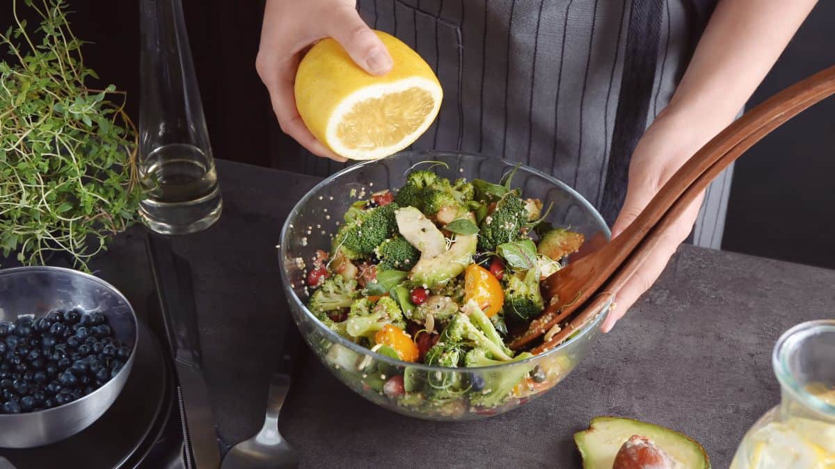 Person squeezing lemon into vegetables.