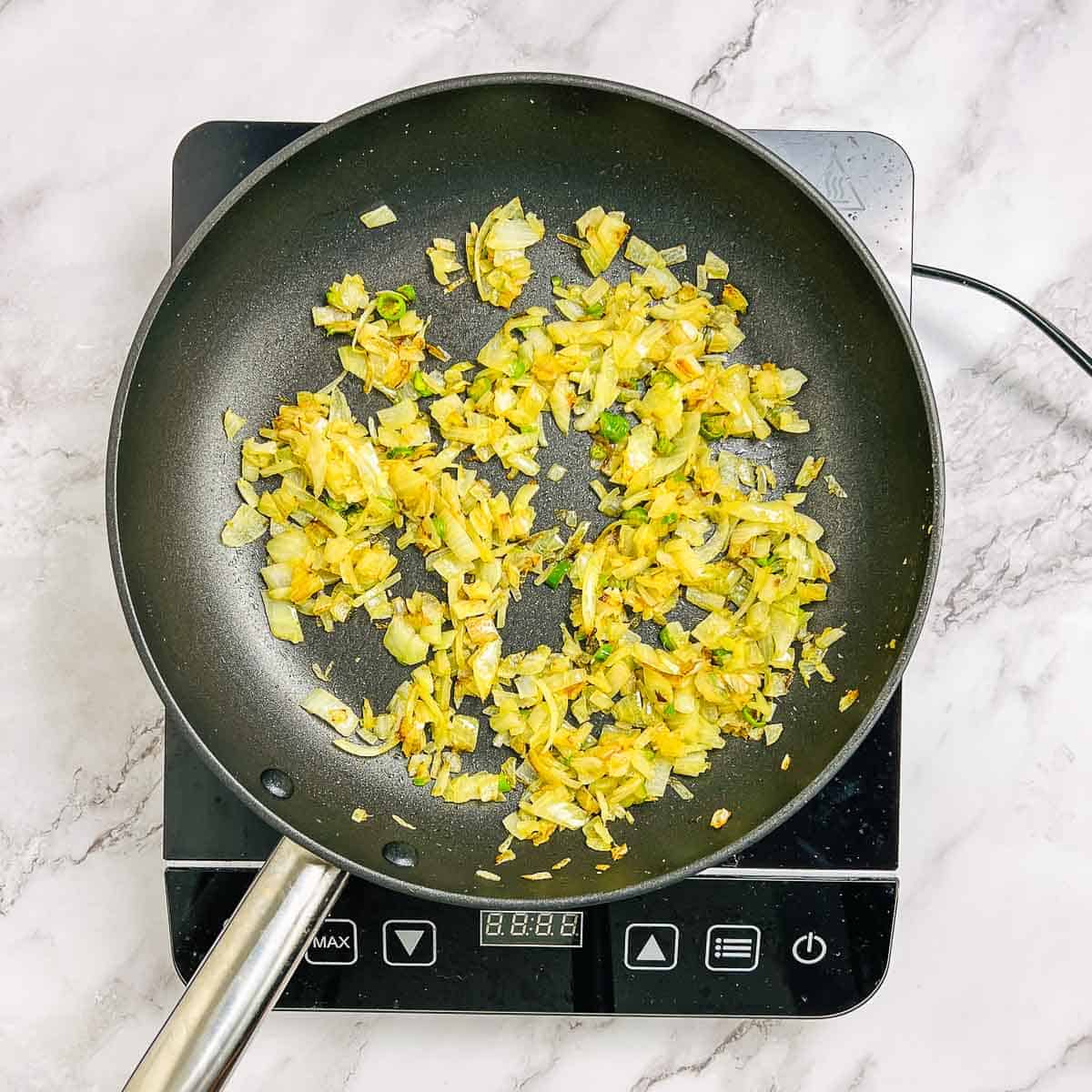 Sauteed onion, ginger, garlic,and chilies in a frying pan.