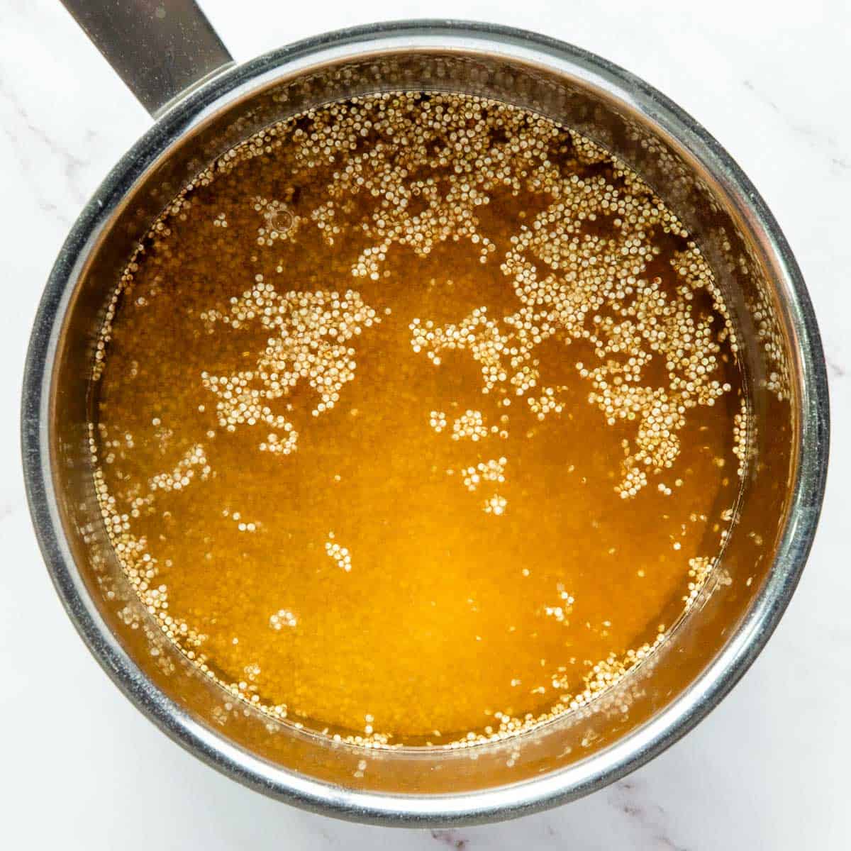 Quinoa cooked in broth in a saucepan.