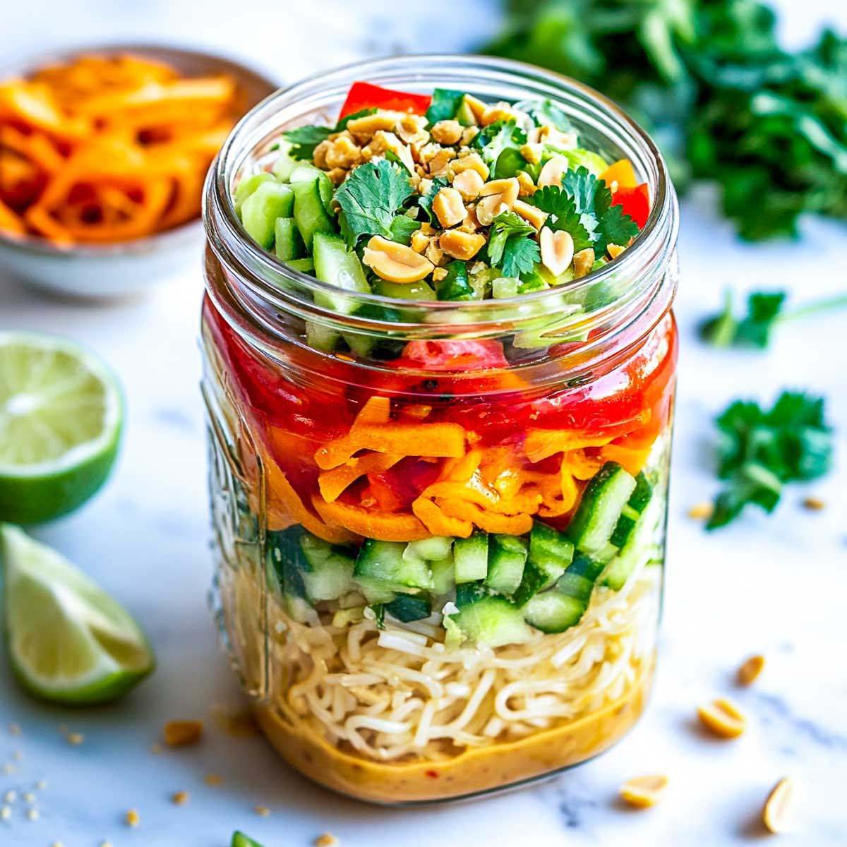 Asian peanut noodle salad jar with cilantro in the background.
