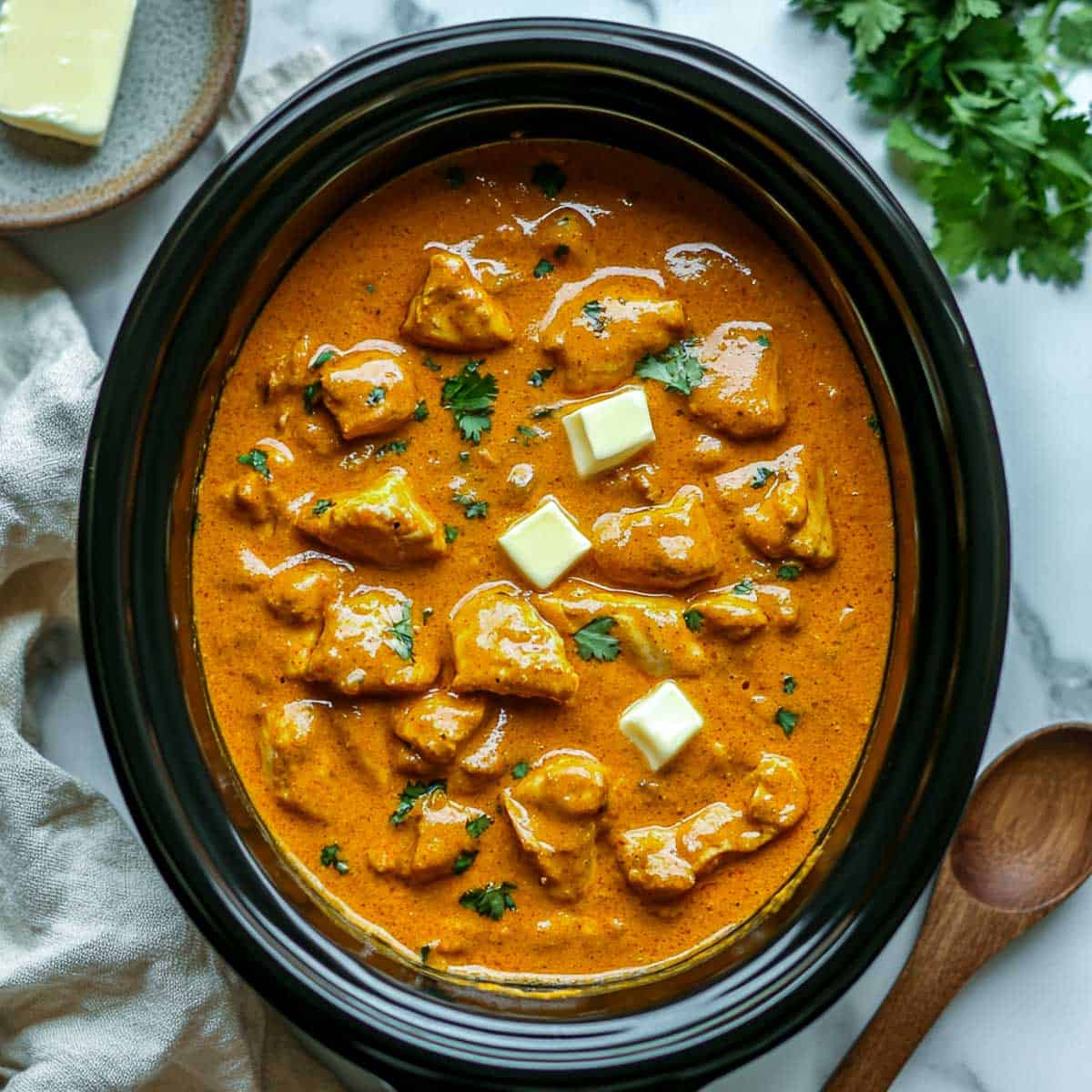 Crockpot butter chicken topped with extra butter.