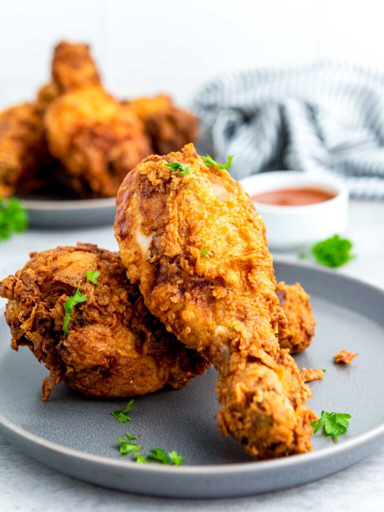 Side view of buttermilk fried chicken on a grey plate.
