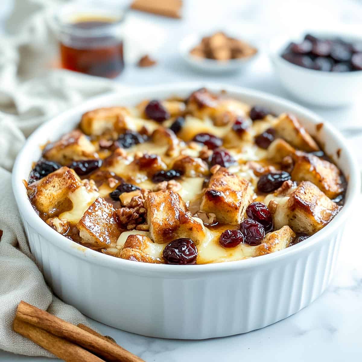 Mexican bread pudding in a baking dish with raisins in the background.