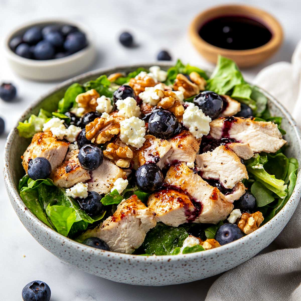 Chicken blueberry salad in a bowl placed on a marble surface.