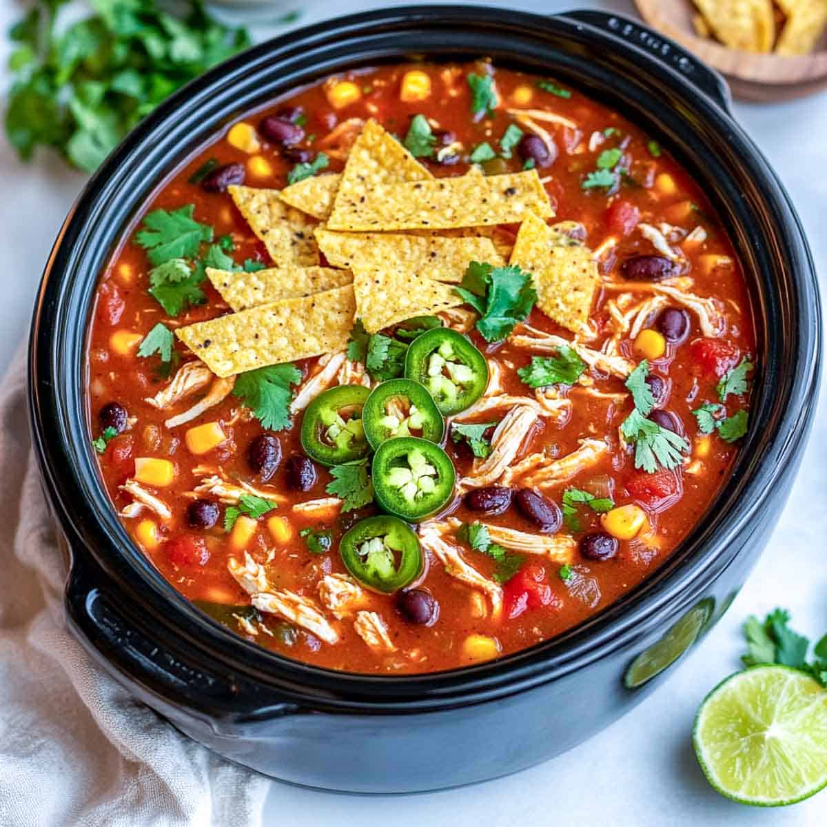 Chicken tortilla soup topped with tortilla chips and jalapeno.