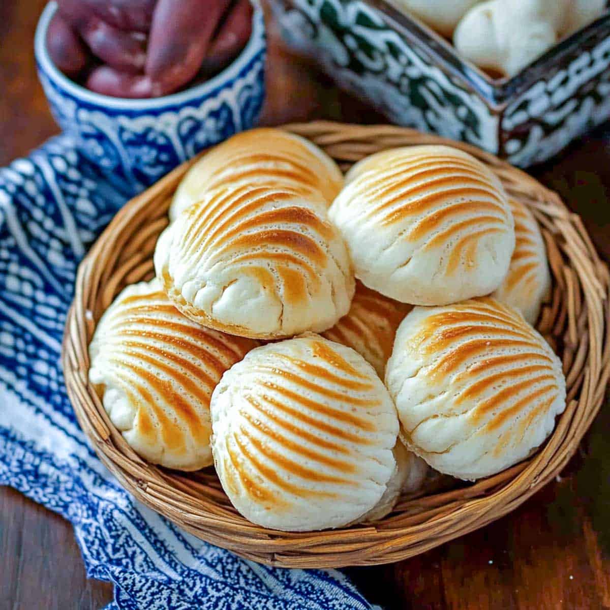 Conchas bread in a basket placed on a wooden surface.