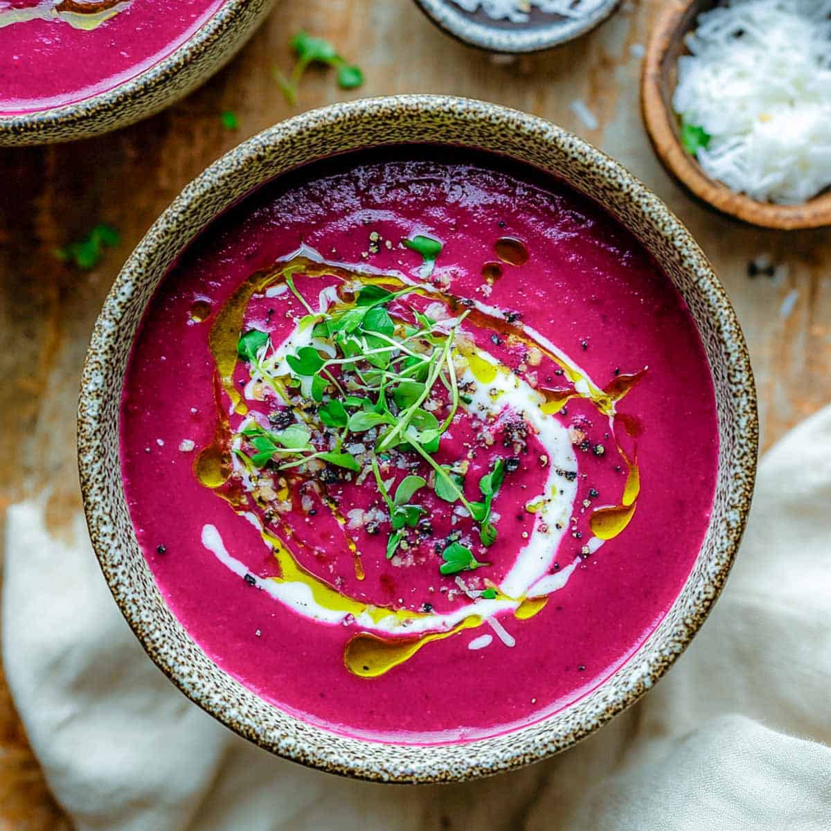 Bright red beet coconut soup bowl with coconut in the background.