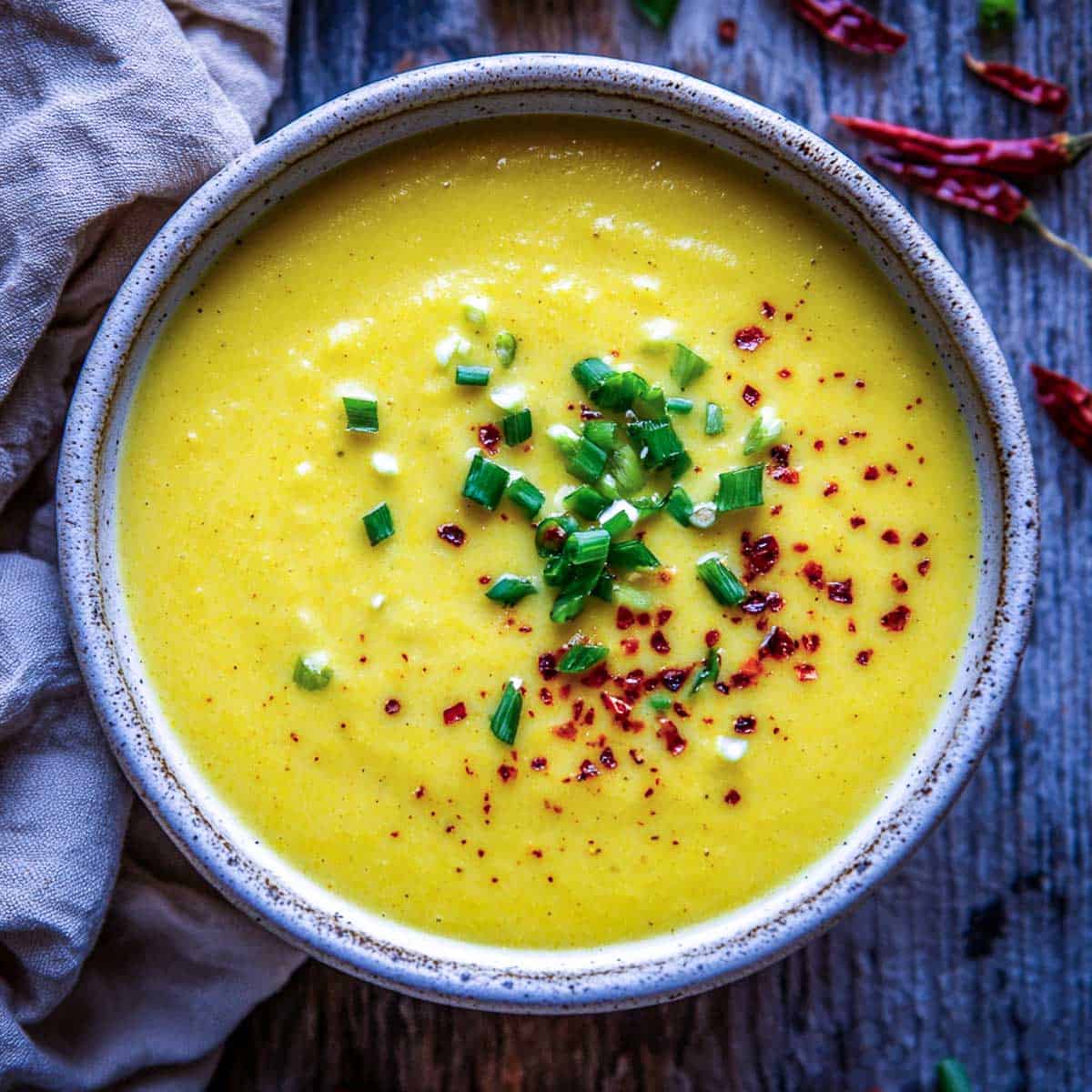 Golden yellow turmeric potato soup in a grey serving bowl.