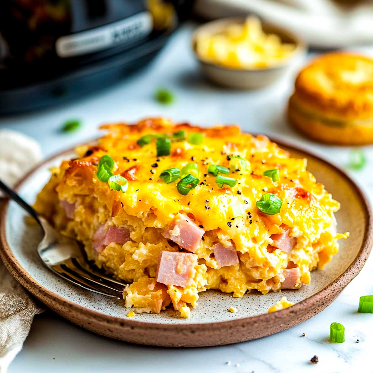 Ham breakfast casserole on a plate with crockpot in the background.