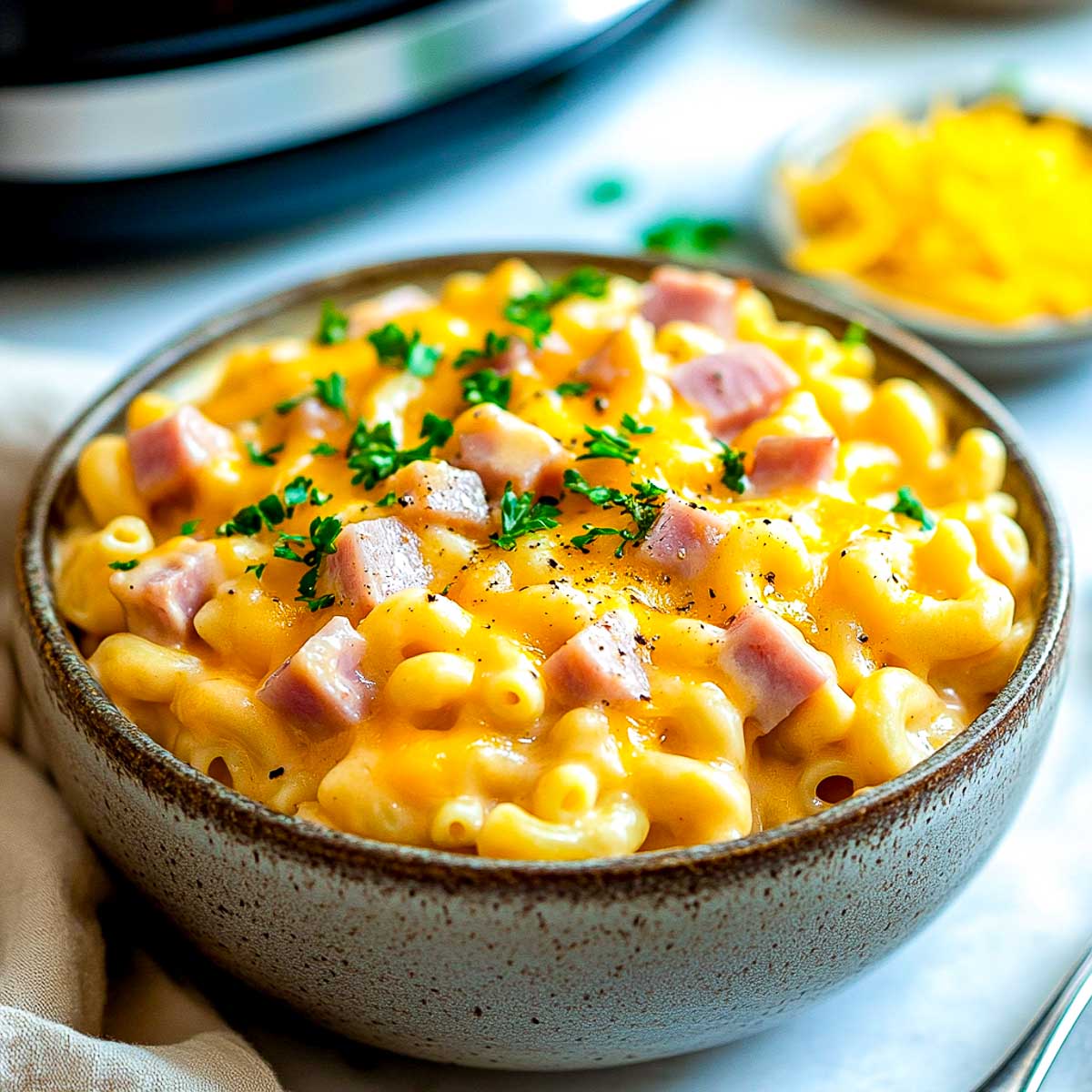 Ham macaroni casserole in a bowl with crockpot in the background.