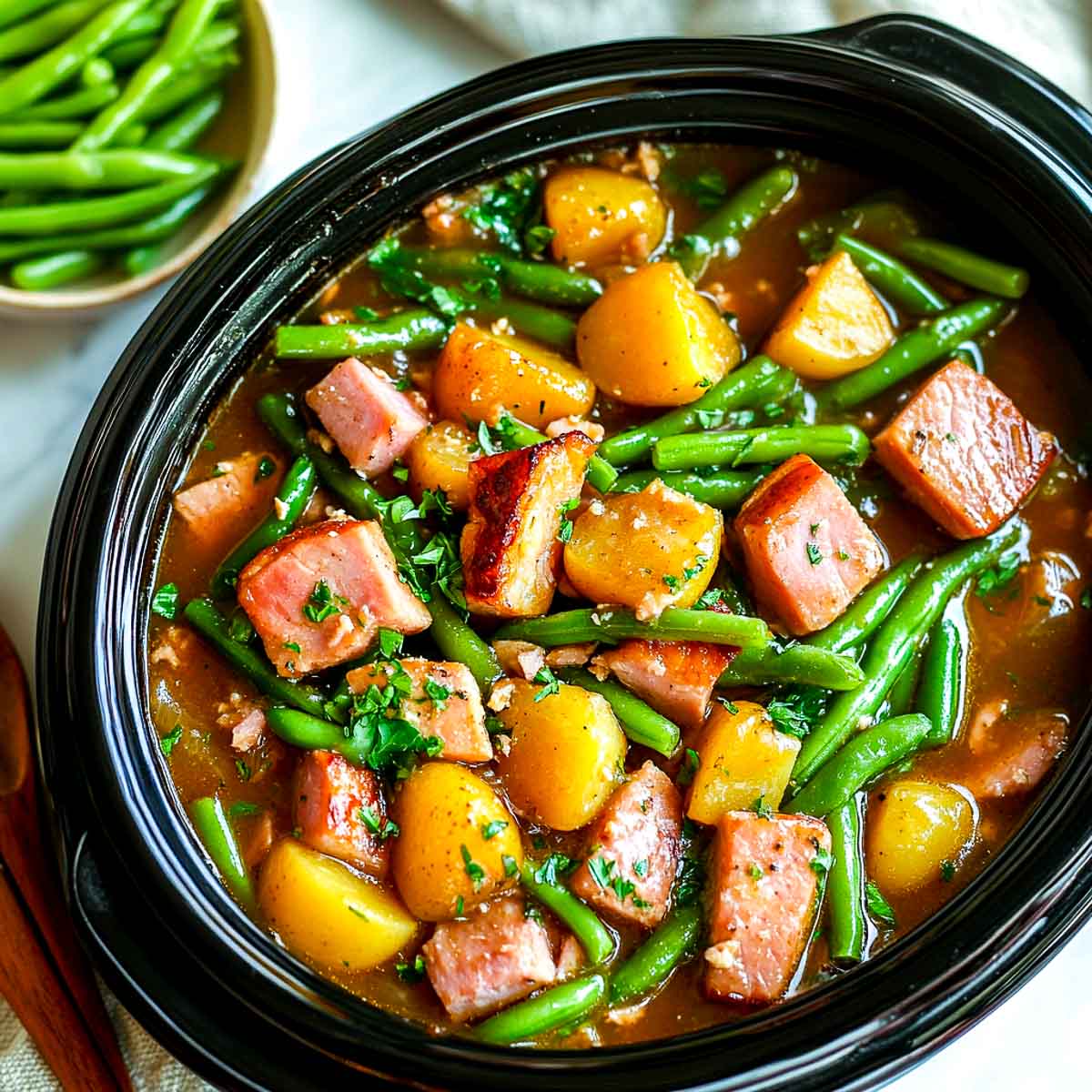 Ham cooked with green beans and potatoes in a crockpot.