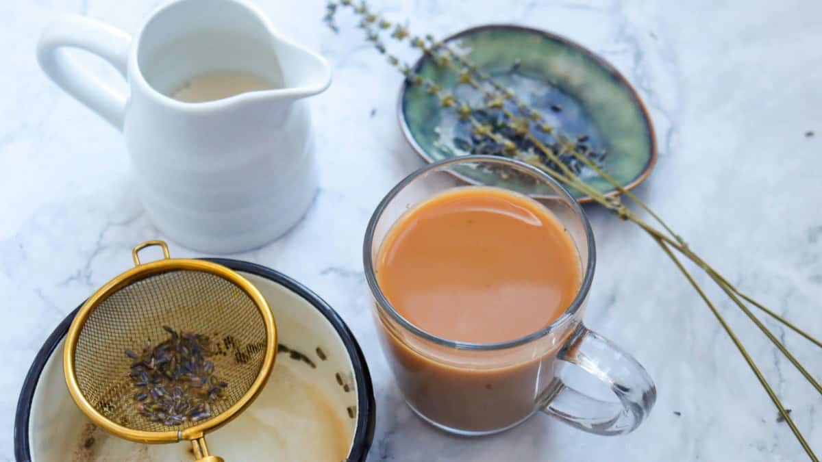 Brewed tea in a cup with saucepan in the background.