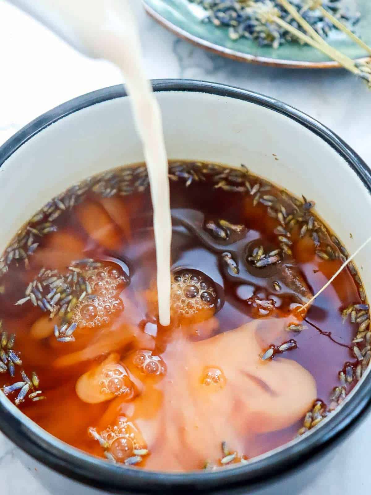 Milk being poured into the brewed tea.
