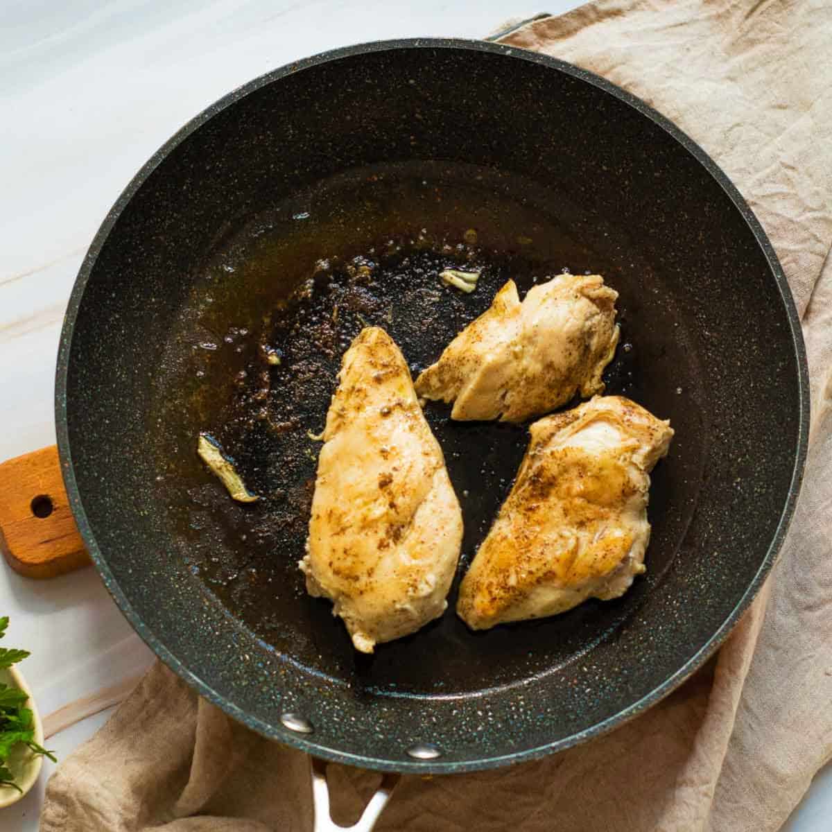 Seasoned chicken seared on skillet.