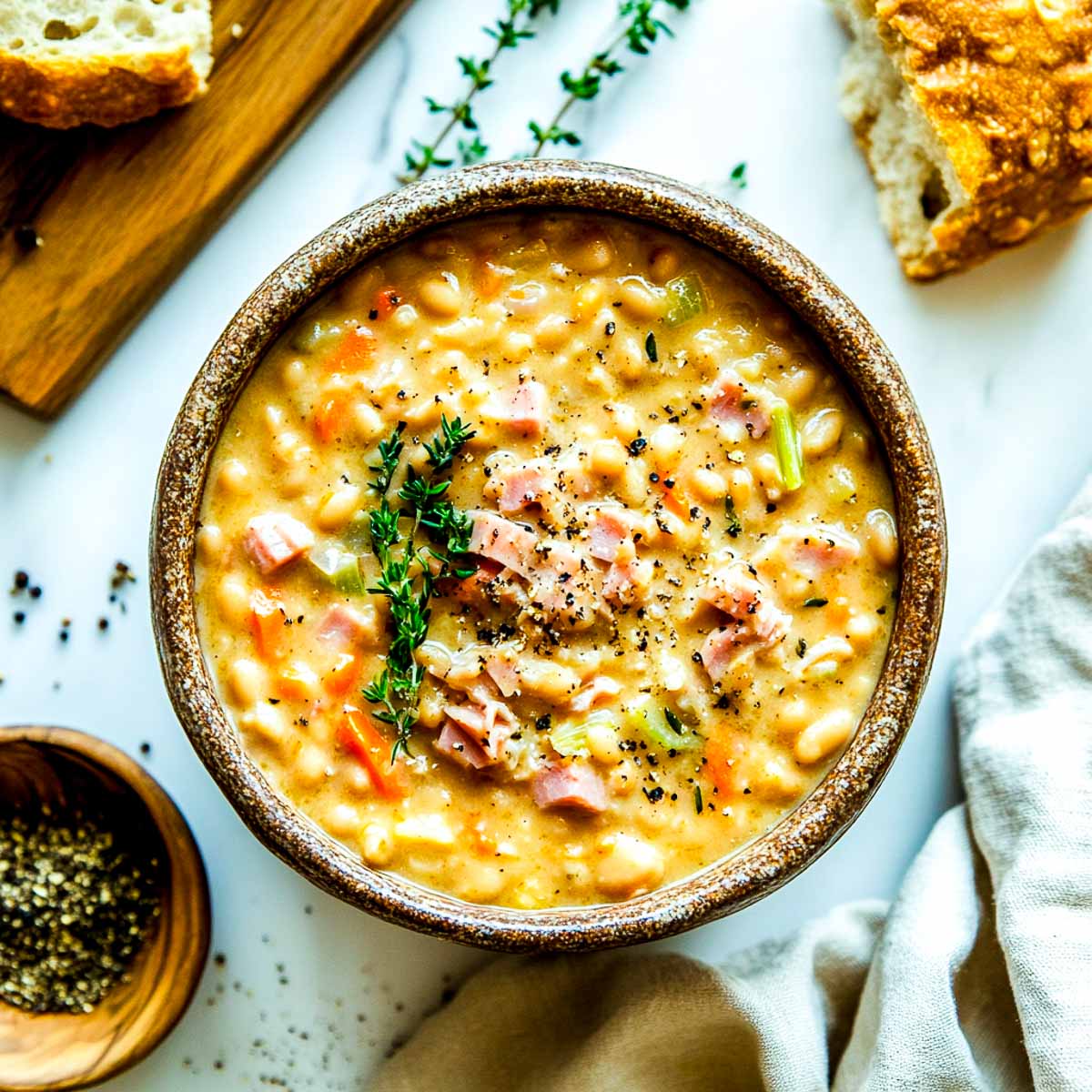 Crockpot Northen bean ham served in a bowl with crusty bread in the background.