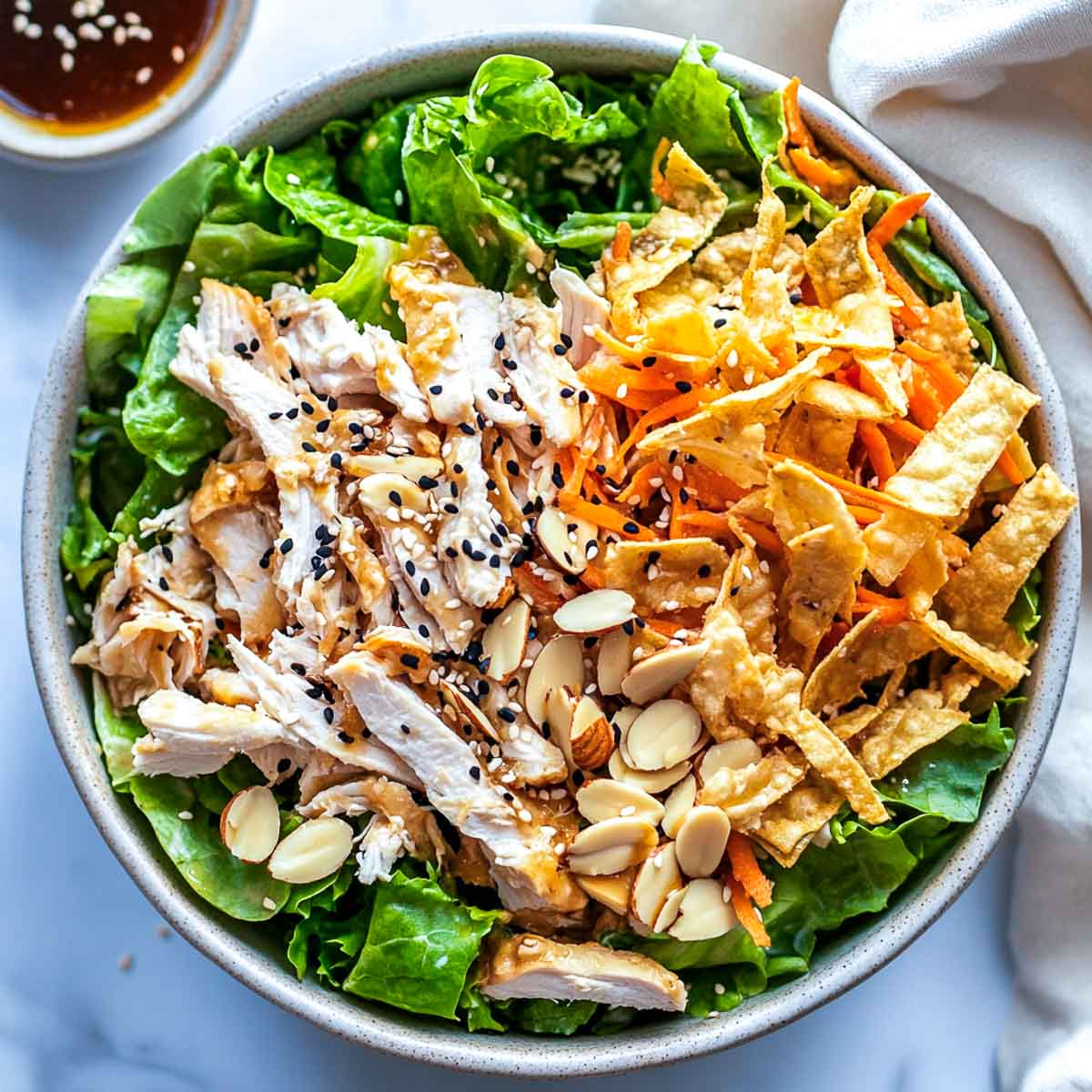 Sesame chicken salad topped with wonton strips.