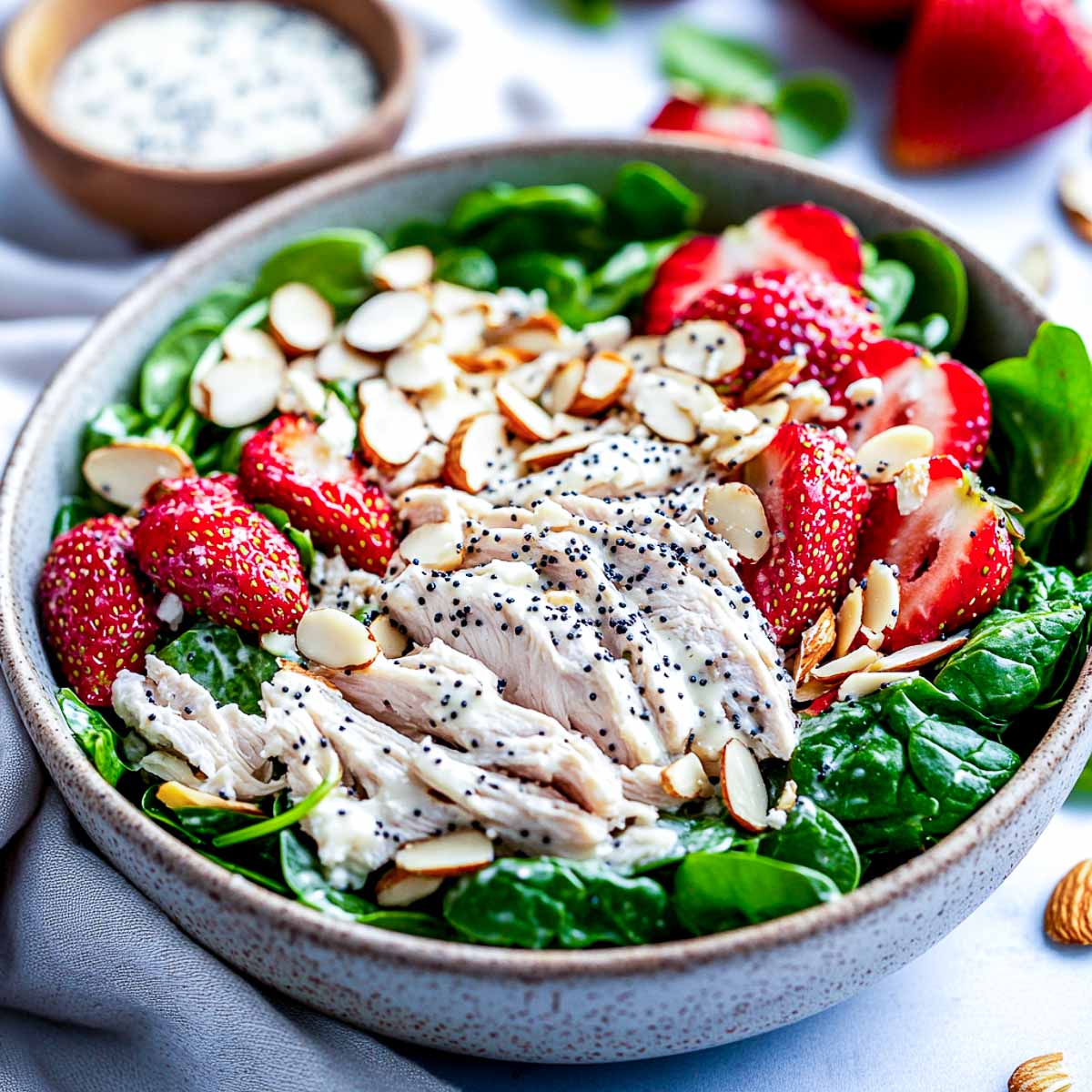 Side view of strawberry chicken salad topped with poppy seeds.