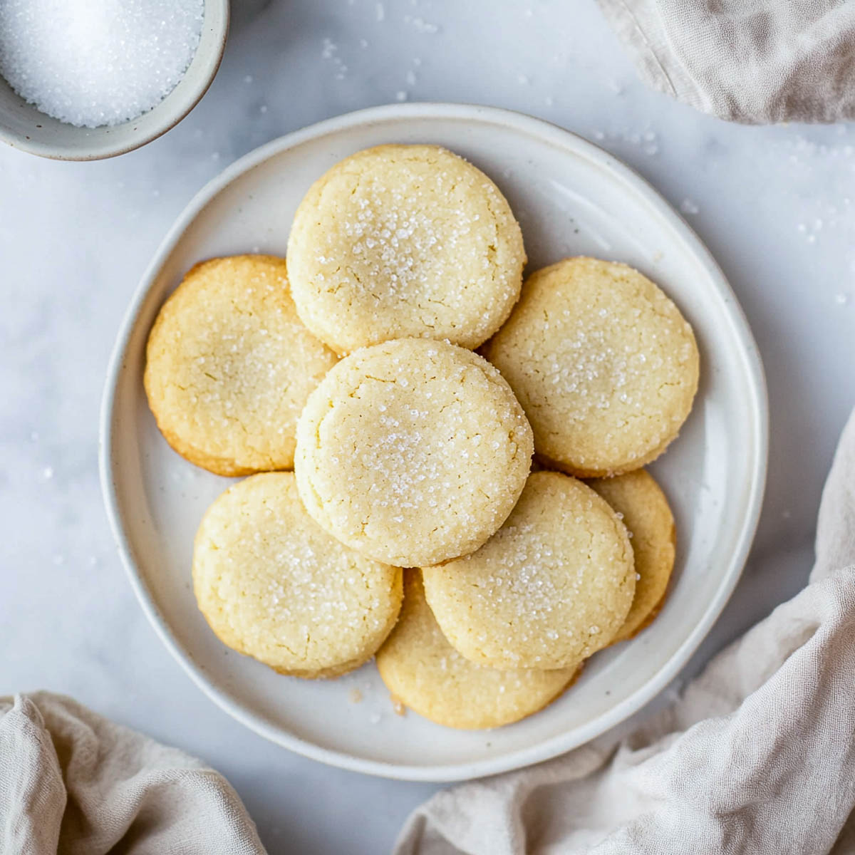 A plate of sugar cookies on a white marble surface.