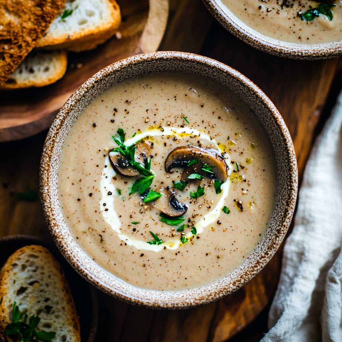 Two bowls of mushroom tarragon soup topped with cream.