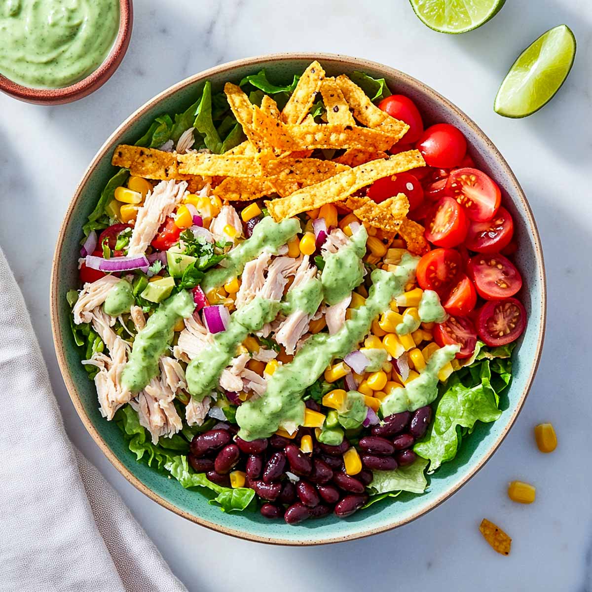 Creamy avocado dressing poured on top with extra dressing bowl in the background.