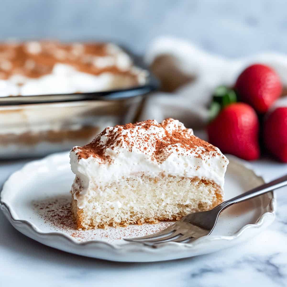 A slice of tres leches cake on a white plate.