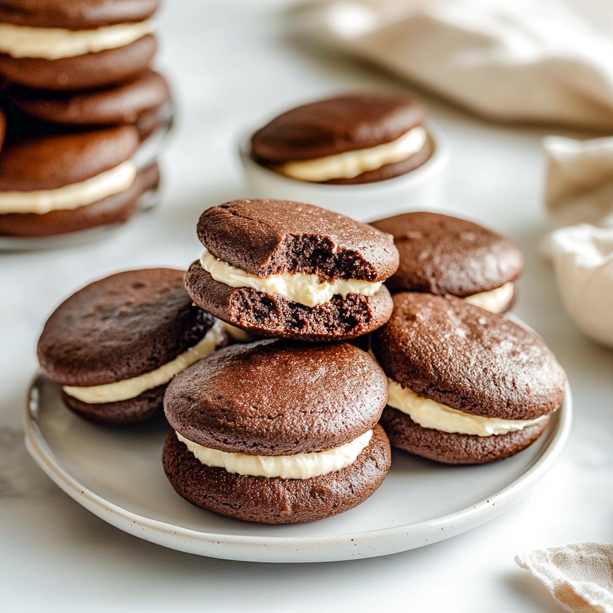 A plate of whoopie pies on a plate with one whoopie pie biten off.