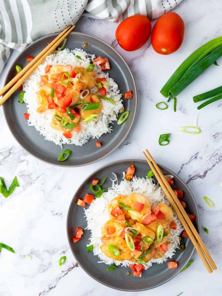 Two plates of bang bang shrimp served over a bed of rice.