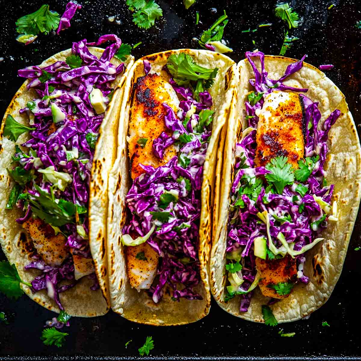 Fish taco assembled and topped with slaw.