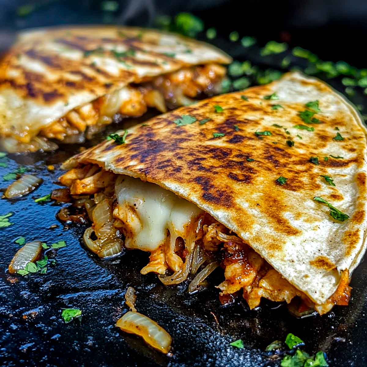 Two cheesy chicken quesadilla garnished with cilantro.